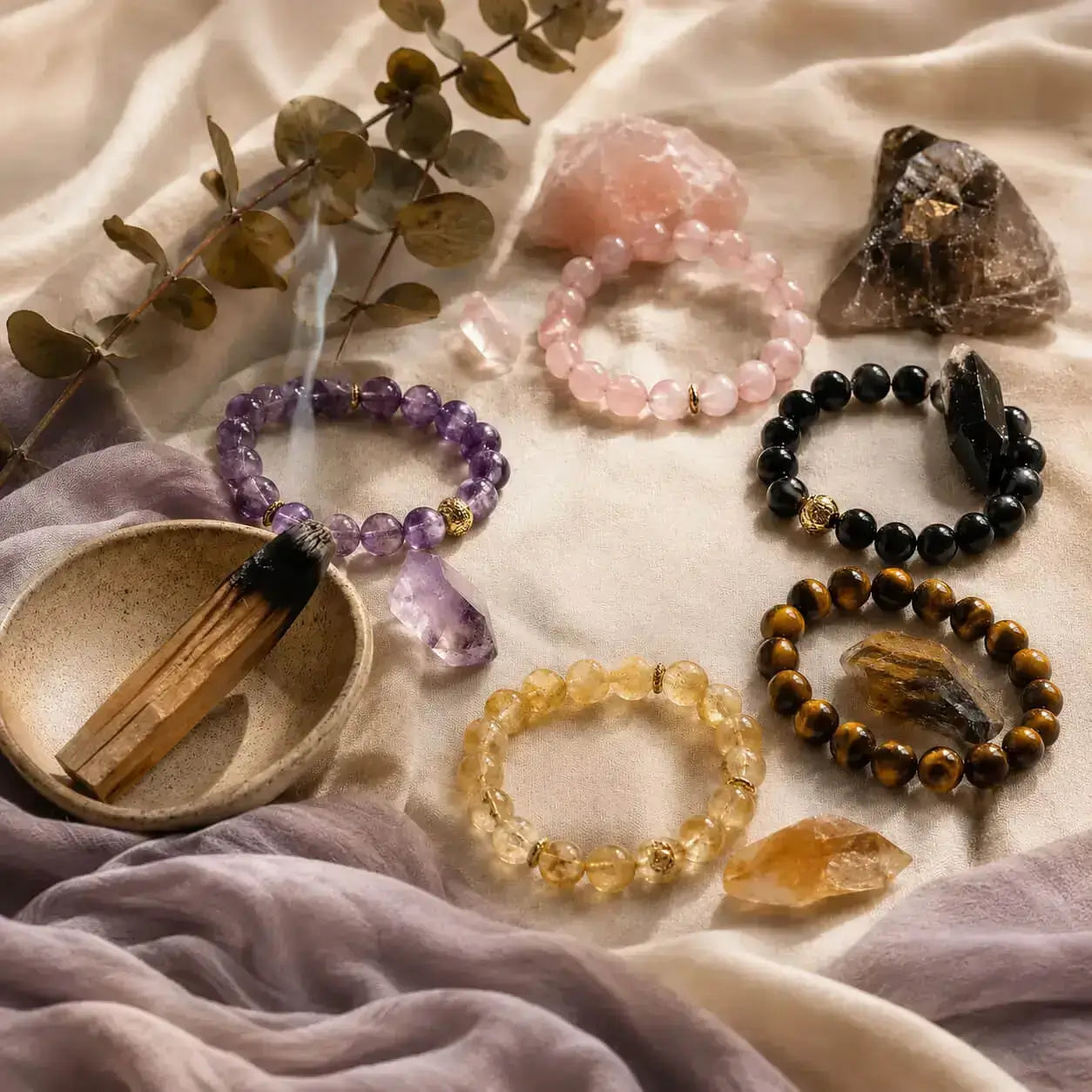AURA Amulet emotional healing crystal bracelet collection with gemstones, dried eucalyptus, and smudging smoke.