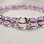 Macro shot of AURA Amulet amethyst bracelet with clear quartz and silver angel wings details.