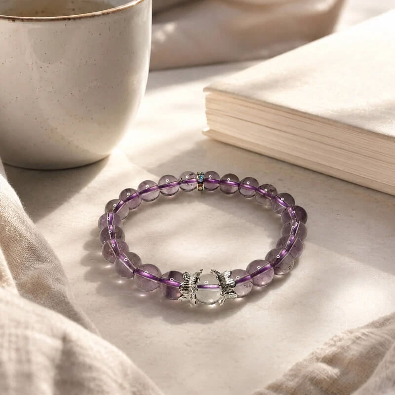 AURA Amulet amethyst crystal bracelet resting in warm sunlight beside a journal for self-care.