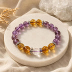 AURA Amulet healing crystal bracelet with amethyst and citrine displayed on white stone with dried floral accents