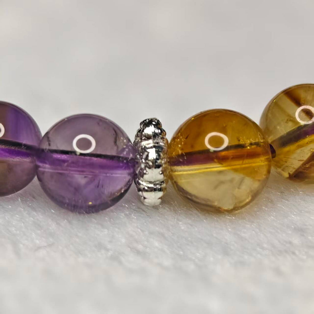 Macro shot of natural amethyst and citrine crystal beads with silver spacers, revealing the authentic gemstone textures.