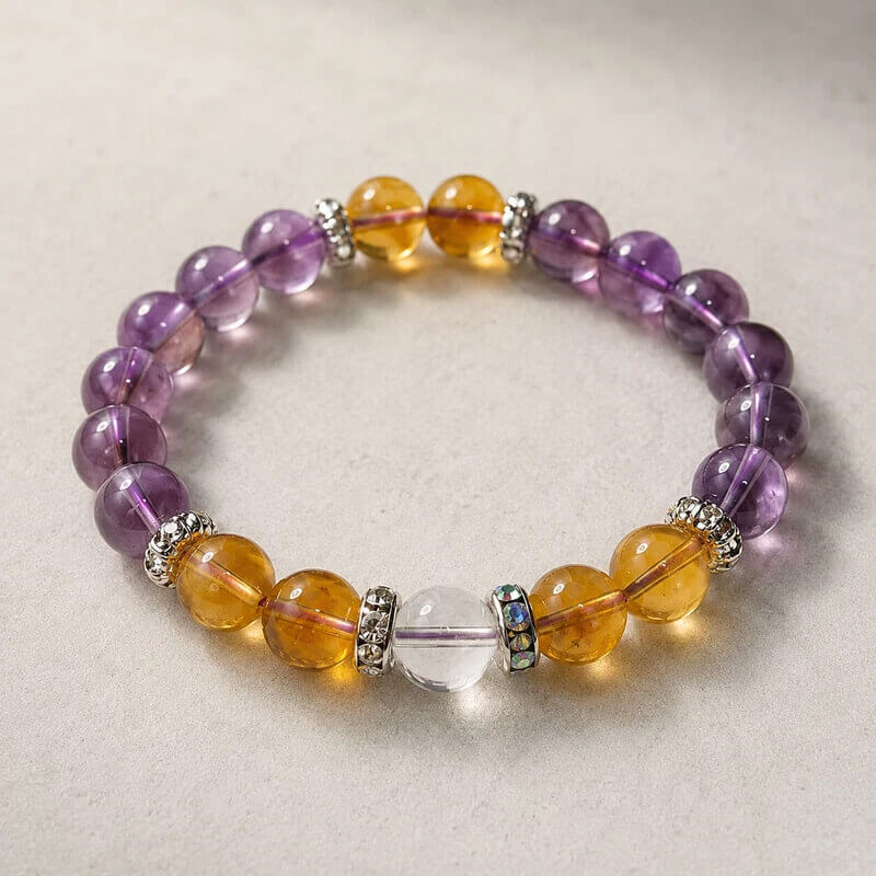 Natural amethyst and citrine crystal bracelet placed on a textured stone surface showcasing calming jewelry vibes.