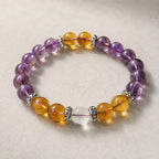 Natural amethyst and citrine crystal bracelet placed on a textured stone surface showcasing calming jewelry vibes.
