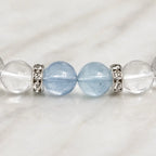 AURA Amulet macro detail of aquamarine bead and silver spacers on a clear quartz bracelet.
