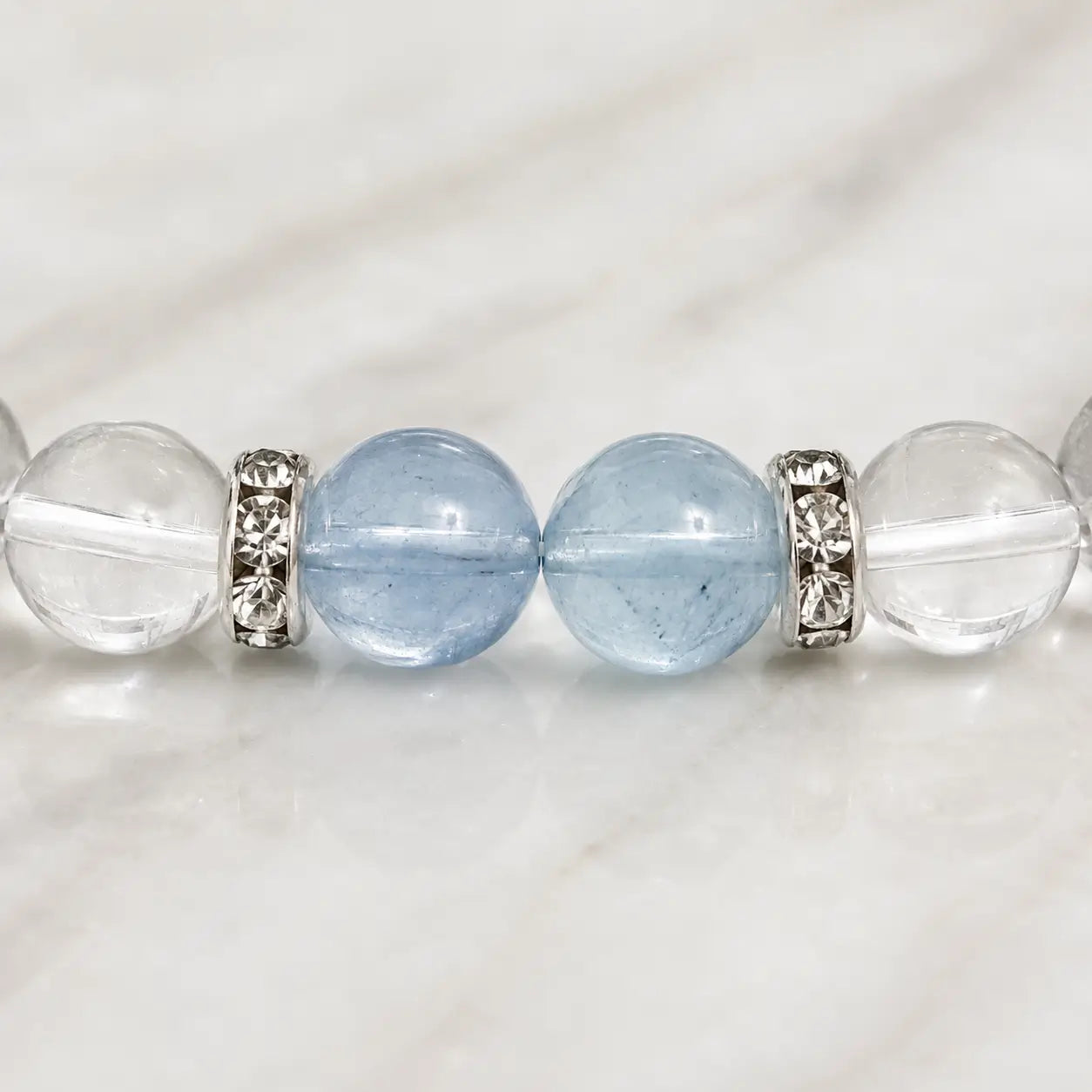 AURA Amulet macro detail of aquamarine bead and silver spacers on a clear quartz bracelet.