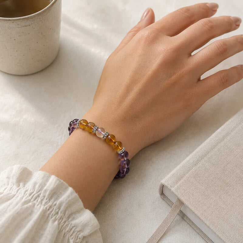 Woman wearing a citrine crystal bracelet during a mindful morning ritual with a cup of tea and a journal.