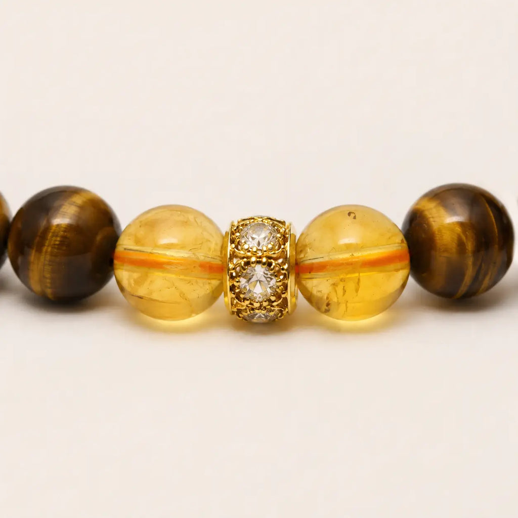 AURA Amulet macro close-up of citrine beads and gold-plated spacer on a tiger eye stone bracelet for wealth.