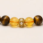 AURA Amulet macro close-up of citrine beads and gold-plated spacer on a tiger eye stone bracelet for wealth.