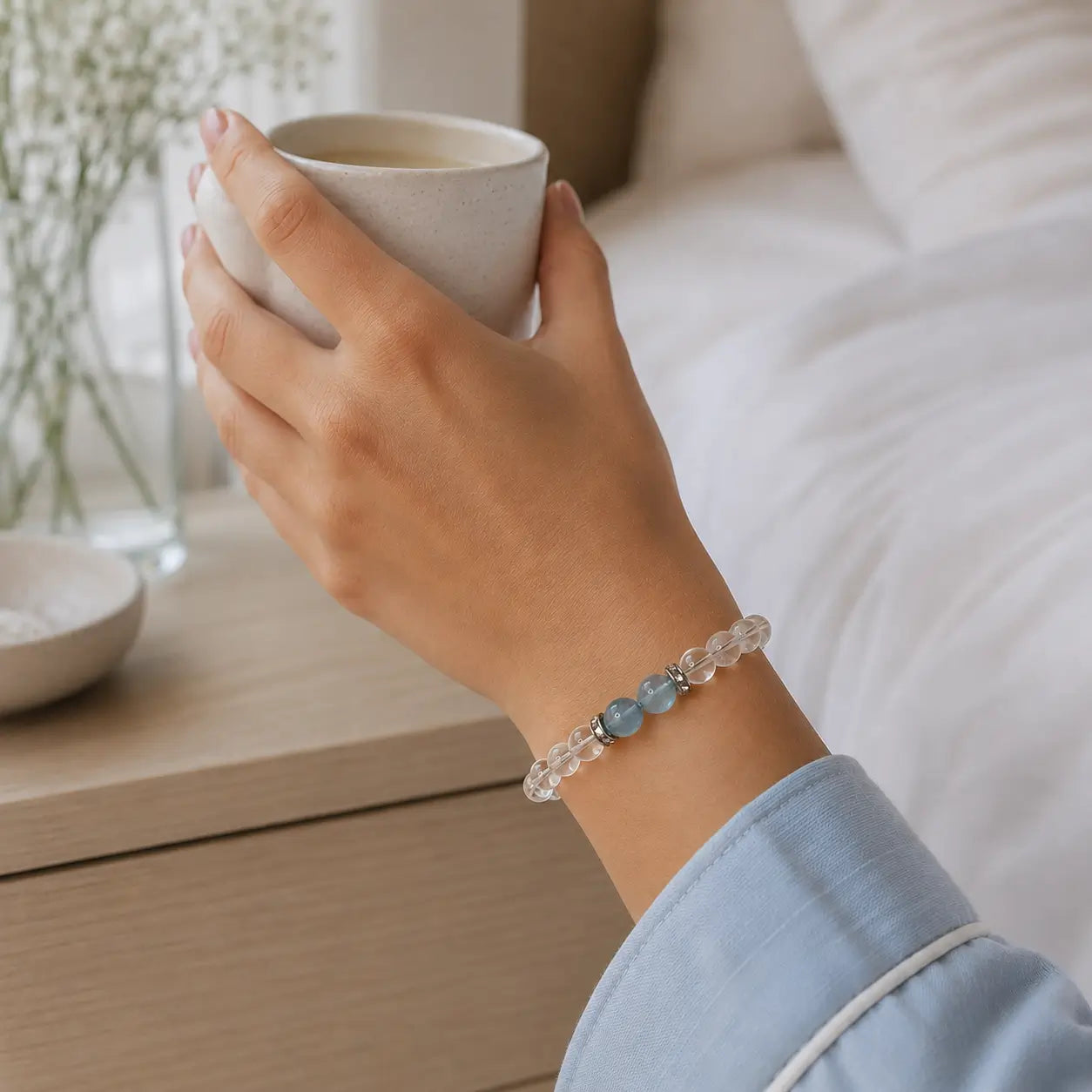 AURA Amulet clear quartz bracelet for meditation worn by woman holding coffee in a cozy setting.