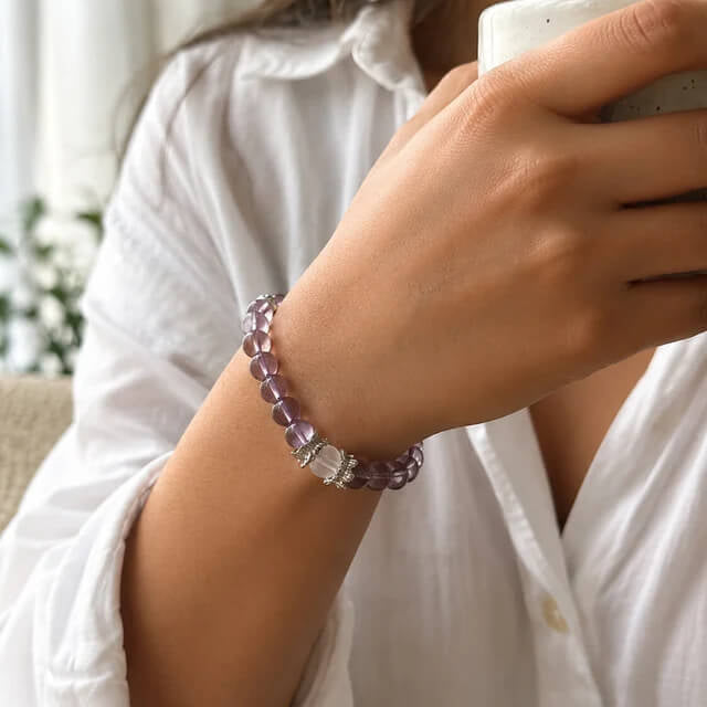 Woman wearing AURA Amulet amethyst crystal bracelet for anxiety relief while enjoying morning coffee.