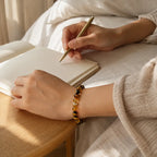 AURA Amulet golden healer bracelet worn while writing in journal, symbolizing crystals for money and success. 