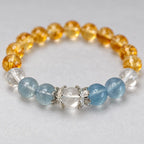 Close-up of a clear quartz center bead between silver-tone lotus caps, with blue aquamarine beads on both sides.