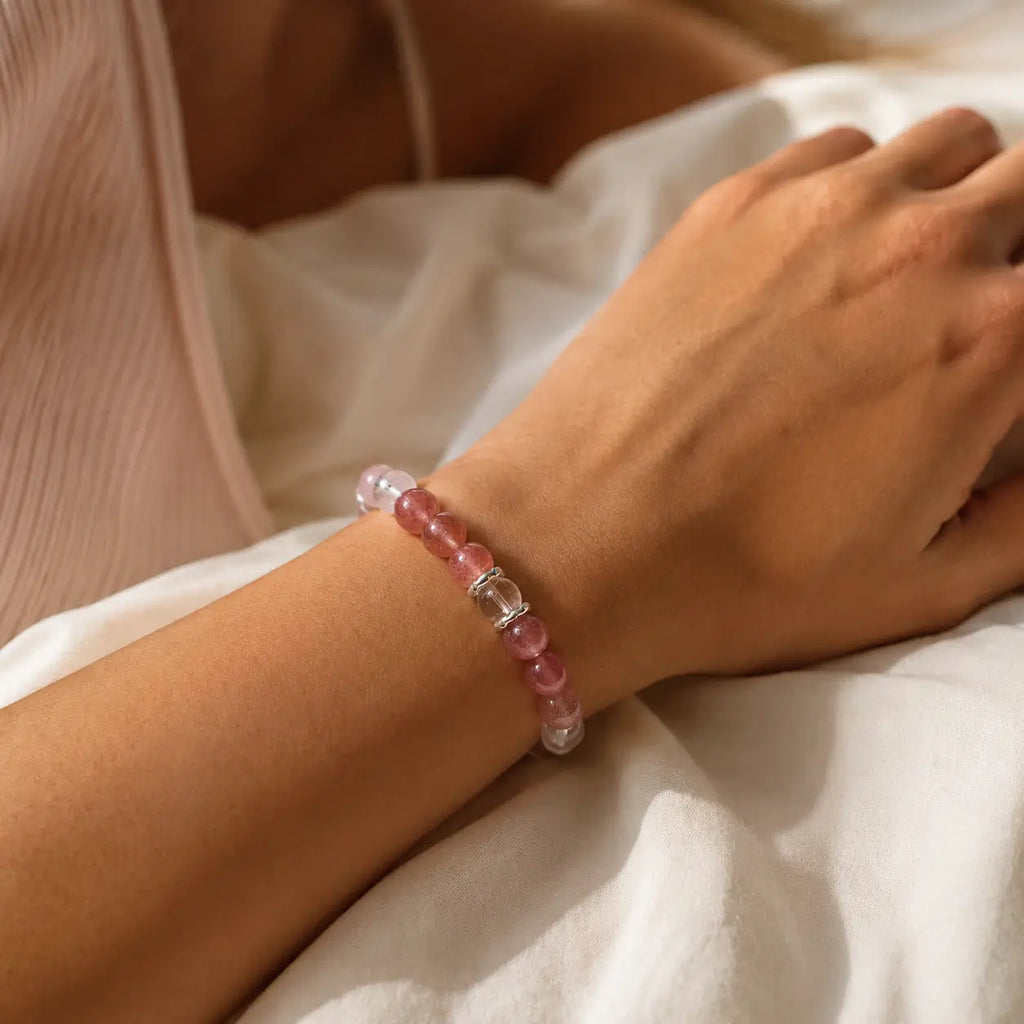 AURA Amulet healing bracelet for women worn on wrist with rose quartz and strawberry crystal in soft sunlight.