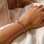 AURA Amulet healing bracelet for women worn on wrist with rose quartz and strawberry crystal in soft sunlight.