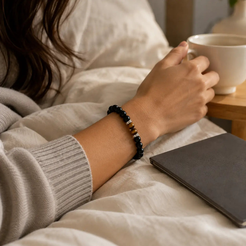AURA Amulet protective black obsidian bracelet worn by woman holding coffee, a daily energy shield accessory. 