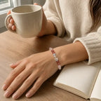 AURA Amulet rose quartz bracelets worn on wrist with coffee and journal, perfect daily self-care accessory.
