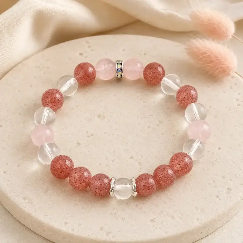 AURA Amulet Strawberry & Rose Quartz Self-Love Bracelet on stone with pink flora, a healing bracelet for women