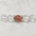 AURA Amulet macro shot of clear crystal quartz and strawberry quartz with silver spacers, a calming anxiety bracelet.